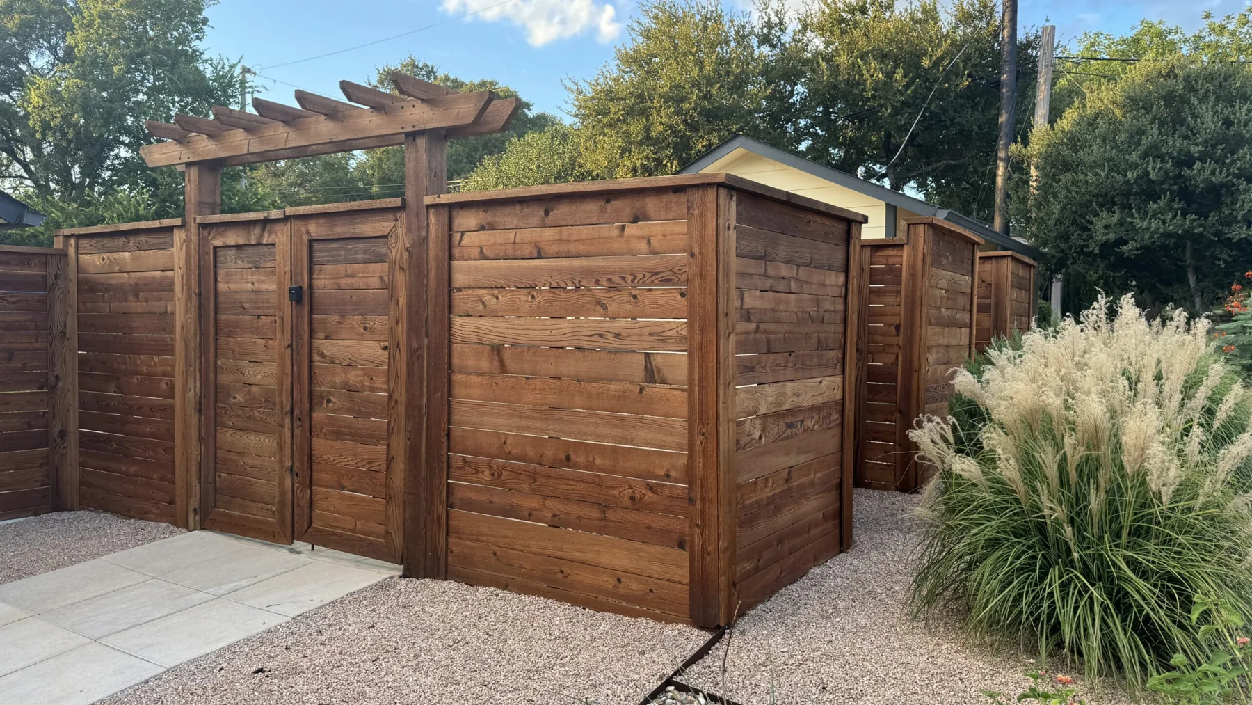 A horizontal cedar privacy fence with a pergola gate, freshly stained by Stain Guys in Georgetown, TX