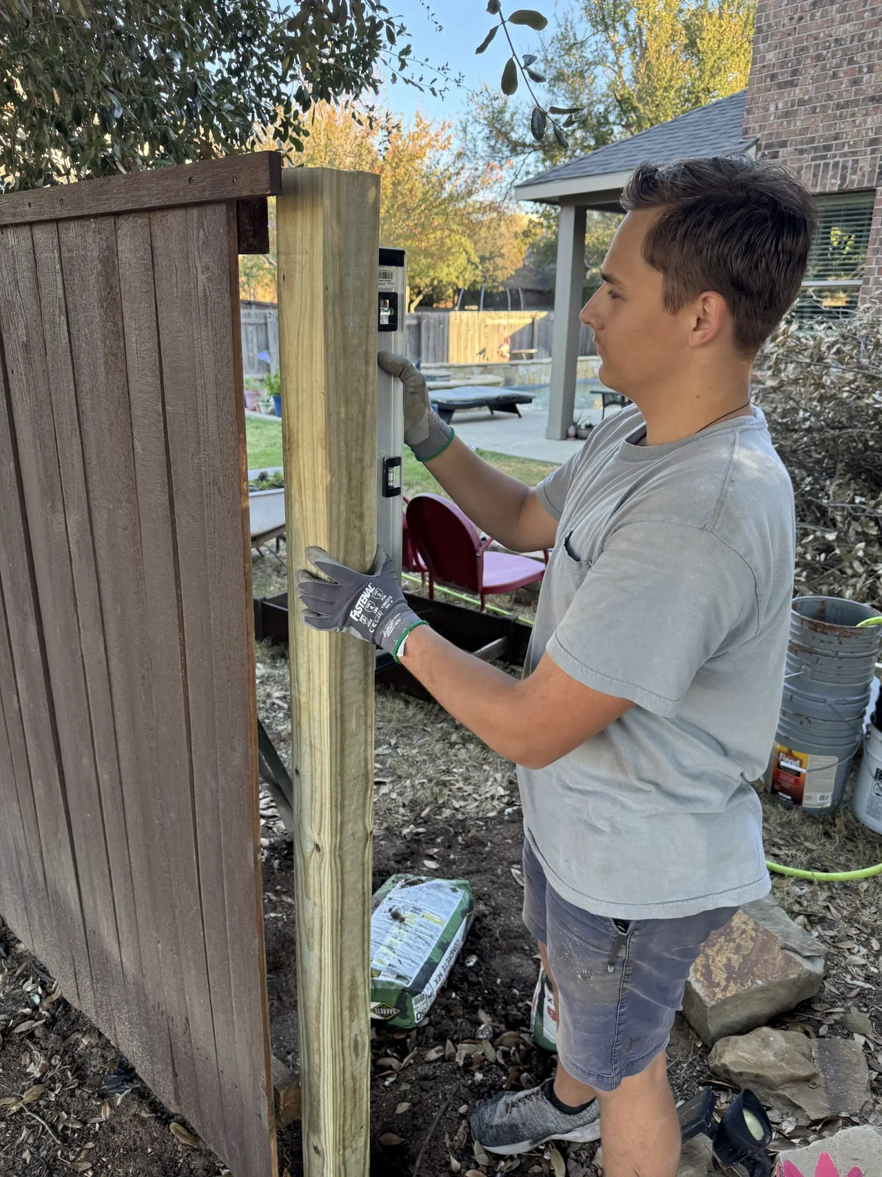 Stain Guys crew member working on a fence post